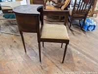 Side view of vintage mahogany telephone bench showing five-legged design and upholstered seat.