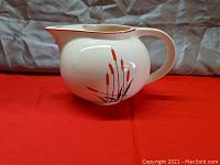 Front angle view of the ceramic water pitcher showing cattail design and shape.