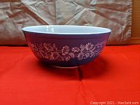 Side view of large Pyrex mixing bowl showing blue exterior with white floral Colonial Mist pattern.