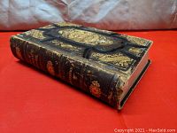 Photo of the book spine showing title, author, and intricate gold embossed details on black leather binding