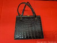 Front view of the vintage alligator purse showing textured black alligator leather and metal clasp closure with two handles.