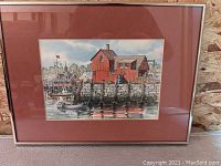Full view of the framed harbor scene print showing red building, pier, and boats.