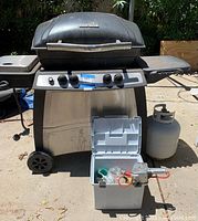 Front view of Char-Broil propane BBQ grill with cooler box and propane tank beside it