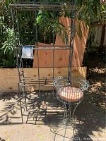 Metal shelving unit shown outdoors with multiple rectangular tiers for plants.