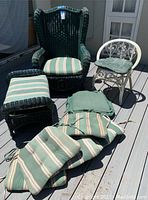 Set of green wicker armchair, green wicker footrest, small white wicker chair, and multiple cushions arranged outdoors on deck.