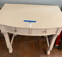 Front view of the white wood desk showing two drawers with glass knobs and curved legs