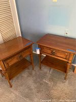 Full view of the pair of vintage Mid-Century Modern nightstands positioned side by side against a wall, showing wood finish and overall shape.