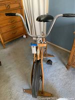 Front view of the vintage Schwinn Exercycle exercise bike showing handlebars, seat, pedals, and flywheel.