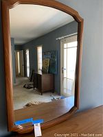 Front view of the Mid-Century Modern mirror with wooden frame reflecting room interior.