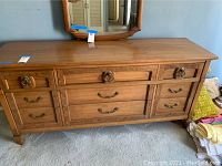 Front view of vintage wooden Mid-Century Modern dresser with multiple drawers and brass handles.