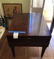 Photo of the vintage wood table showing top surface, drawer front, and legs, highlighting its rectangular shape and dark wood finish.