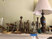 Collection of brass candleholders and small decorative items on mantle shelf.