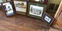 Photo of four framed signed limited edition prints displayed on a wooden floor showing rustic and natural scenes