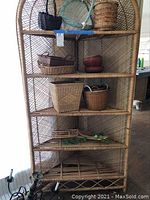 Full view of vintage cane corner shelving rack with baskets on shelves.