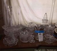 Assortment of various crystal and cut crystal pieces including bowls, vases, candlesticks, and covered candy dishes arranged on a table.
