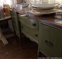 Full view of green buffet cabinet showing curved drawer fronts, side cabinet doors, and decorative legs.