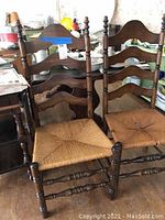 Four vintage wooden chairs, two with arms and two without, showing cane seat weaving and wood frames.