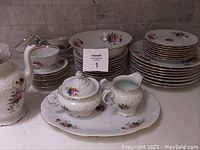 Full set including plates, bowls, serving platter, coffee pot, creamer, sugar bowl, cups and saucers arranged together.