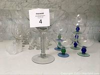 All stemware pieces arranged on a counter showing various types of glasses including fishbowl with colored stems.