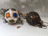 Both lamps displayed side by side on white marble surface. Shows comparative size and detail of both items.