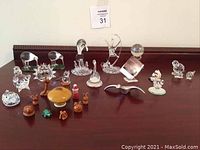 Wide shot of entire collection showing crystal animal figurines, greenstone birds, and pottery animal village set on wooden surface