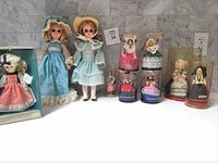 Complete lot of vintage dolls arranged on a table, showing two Vogue dolls, Uneeda Miss USA doll in box, and five French Poupee dolls in cases.