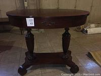Front view of the antique solid wood oval table with single drawer and pedestal base.