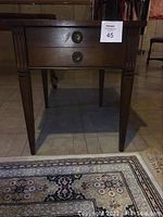 Front view of the solid walnut end table showing two drawers with brass pulls and tapered legs