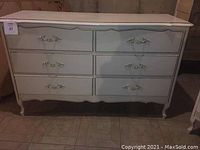 Long table dresser with 6 drawers, white French Provincial style with curved legs and decorative handles, scuffed surfaces.