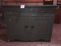 Front view of the solid wood bottom cabinet of the antique cupboard showing two drawers with brass handles and two doors with round knobs, with visible paint wear and chipping