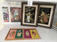 Two framed Asahi Japan mother of pearl bird artworks with floral details, plus four mythological character prints (two framed, two unframed) displayed on a flat surface.