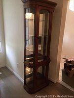 Full view of tall wooden curio cabinet showing beveled glass and rounded edges.