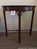 Front view of half-moon wooden side table showing curved top, three legs, and decorative supports.