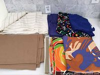 Overview of folded and rolled assorted vintage fabrics including solid, striped, and multicolored prints.