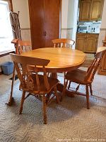 Five-piece honey oak dining set comprising oval pedestal table and four matching spindle-back chairs