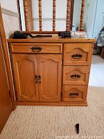 Front view of wooden cabinet showing four drawers and double door compartment below large drawer.