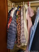 Photo showing multiple ladies jackets hanging on a closet rod including purple puffer jacket, plaid jacket, leopard print fleece jacket, cream jacket and pink jacket.