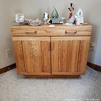 Front view of solid oak TV cabinet with decorative items on top and two doors closed.