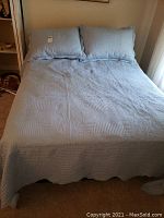 Blue matelasse quilt and matching pillow shams on a double bed