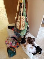 Four quilted bags hanging on hooks and a large assortment of scarves in bags and on the floor.