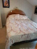 Full view of bed made up with Paris-themed bed linens on full mattress and boxspring, wooden headboard visible