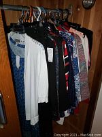 Full view of assorted women's tops, blouses, sweaters on hangers showing multiple colors and styles