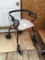 Front side view of Dolomite folding mobility cart showing padded seat, handle with brake lever, and four wheels.