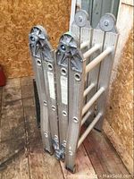 Photo showing the ladder folded in one closed position standing upright, showing hinge mechanisms and edges.