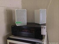 Sony receiver with Realistic speakers placed on top, visible wall background