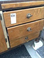Closed view of the wooden cabinet with three drawers and metal and decorative handles.