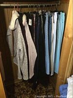 Clothes hanging in closet showing 3 sweaters and multiple pairs of jeans in size 4