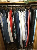 Various women's pants including jeans, capris and slacks hanging on rod