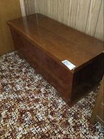 Side view of the rectangular wooden cedar chest with the flat top and wood grain visible, showcases its condition and form.