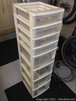 Front and side view of tall white plastic 8-drawer storage organizer with wear and scuffs.